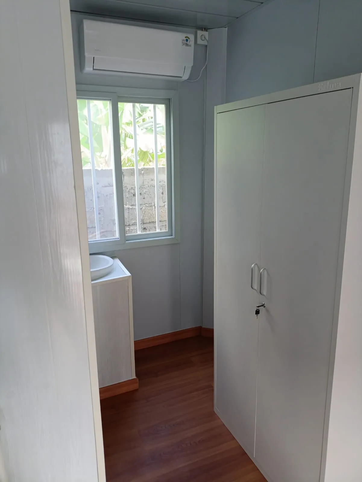 Interior kamar Deluxe Wisma Bludru dengan AC, wastafel, dan lemari, finishing sekelas apartemen
