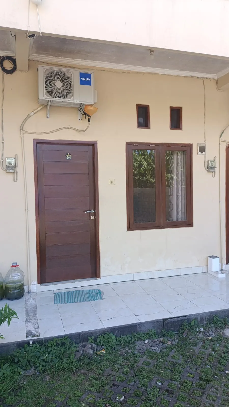 Tampak depan kamar Standard Wisma Bludru dengan pintu kayu dan AC